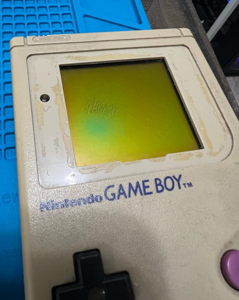 A Game Boy missing the plastic screen cover. It also has some LCD damage.