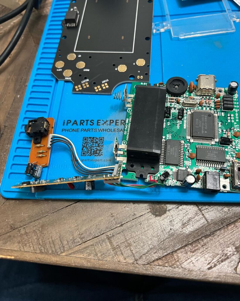 A Game Boy main board with a replacement screen near it.