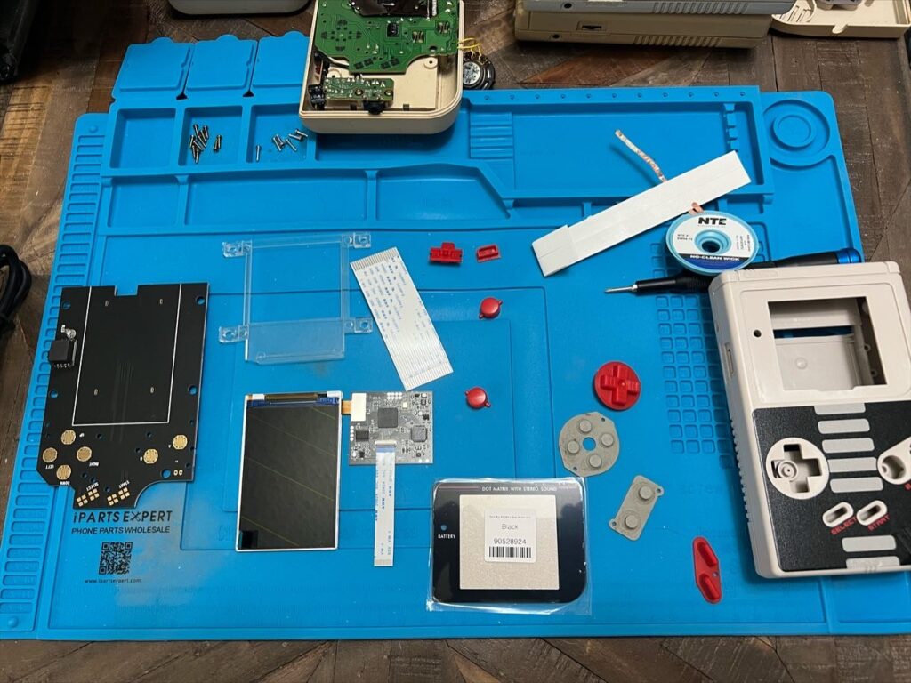 Electronics and Game Boy parts spread on a work mat.